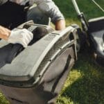 Mężczyzna wymienia worek w kosiarce spalinowej w ogrodzie