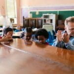 Dzieci klaszczą z nauczycielką podczas lekcji muzyki w klasie