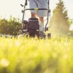 Osoba kosząca trawnik kosiarką w słoneczny letni dzień