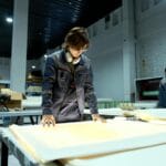 Pracownik w hali produkcyjnej kontroluje arkusze materiału