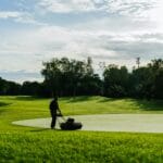 Ogrodnik kosi trawę kosiarką na polu golfowym w słoneczny dzień