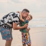 Ojciec przytula syna na piaszczystej plaży w słoneczny dzień