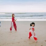 Rodzina azjatycka bawi się i śmieje na piaszczystej plaży