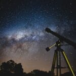 Sylwetka teleskopu na tle rozgwieżdżonego nieba z Drogą Mleczną