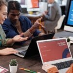 Zespół w nowoczesnym biurze omawia cyfrową transformację przy laptopach
