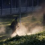 Mężczyzna kosi trawnik kosiarką spalinową w słońcu
